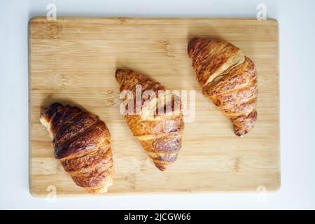 Close up of golden croissants on a wooden tray Stock Photo