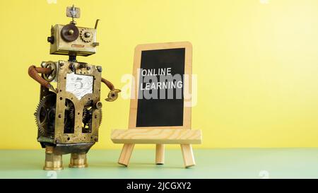 The robot stands at the blackboard with the inscription online learning. Stock Photo