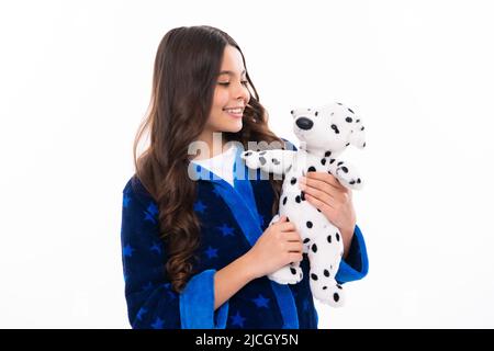 Teen girl feeling relaxed in pajamas, good morning. Teenage girl embracing toy. Childhood, toys and kids. Cute teen girl cuddling favorite fluffy toy Stock Photo