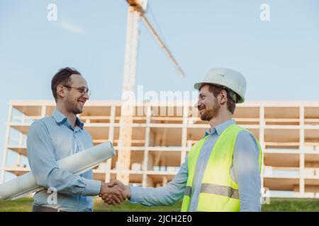 Hanshake seals an agreement at construction site. Architect and consumer handshaking on construction site. building, teamwork, partnership concept Stock Photo