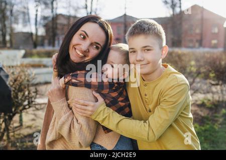 a happy mom plays with her two sons in a spring park. Stock Photo