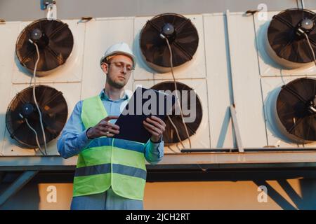 Service hvac engineer in uniform inspecting industrial refrigeration system Stock Photo