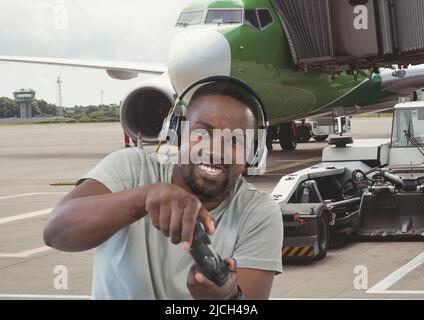 Composite image of african american man playing video games against airplane at the airport Stock Photo