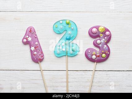 Top view of 1 2 3 colorful numbers lollipops on white wooden background Stock Photo