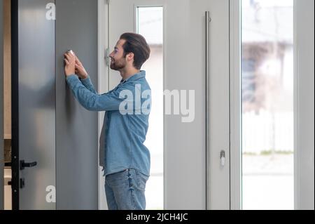 Man checking home control panel touching wall Stock Photo