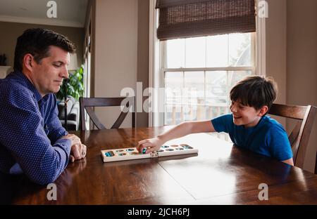 Boy and his father having fun playing a game together at home. Stock Photo