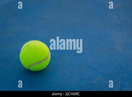 Close up of yellow tennis ball on a blue hard court. Stock Photo