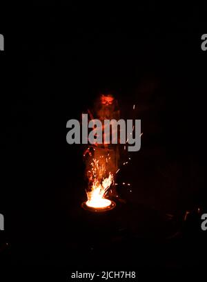 a man putting wood into a fire pit at night Stock Photo