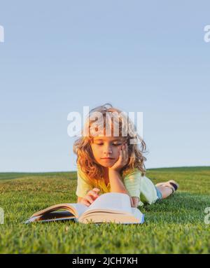 Kid read book in park on green grass lawn. Stock Photo