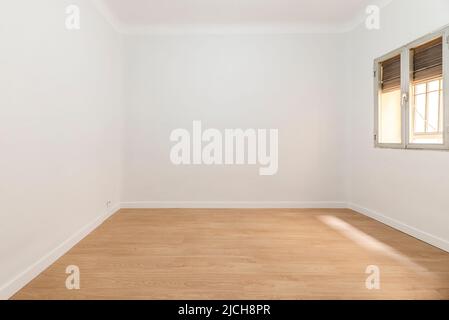 Empty room with aluminum window with shutter half up, wooden floorboards and plain white painted walls Stock Photo