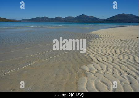 Luskentyre beach, Isle of Harris. Blue sky, mountains in background, sea and wavy lines of sand in foreground. No people. Tranquil, summer scene. Stock Photo