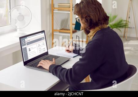 Businessman using laptop fills out online survey checklist by registering on website. Stock Photo