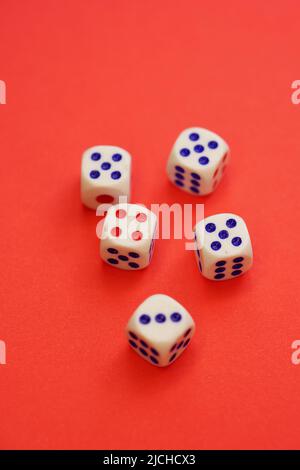 Five dice with different numbers on a red table. Stock Photo