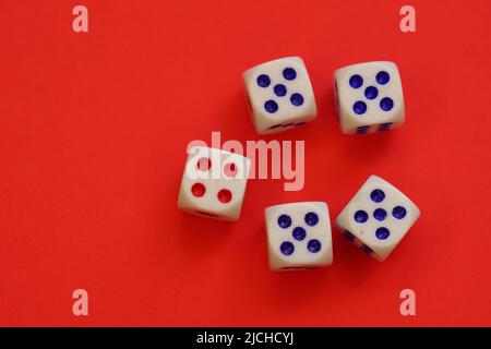 Dices with different numbers on a red table. Stock Photo