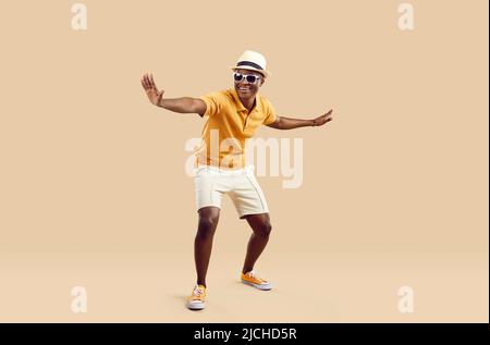 Cheerful stylish african american man having fun dancing on light beige background. Stock Photo