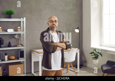 Portrait of serious confident man in glasses standing with his arms crossed in home office Stock Photo