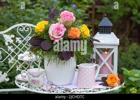 arrangement with bouquet of roses, porcelain and vintage lantern Stock Photo