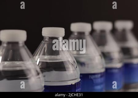 Small water bottles placed in perspective view, and on a black background Stock Photo