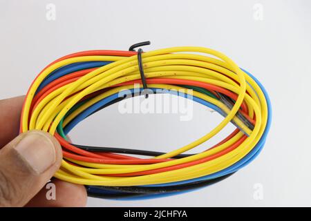 Pack of multicolored wire tied with a small piece of cable held in hand on white background Stock Photo