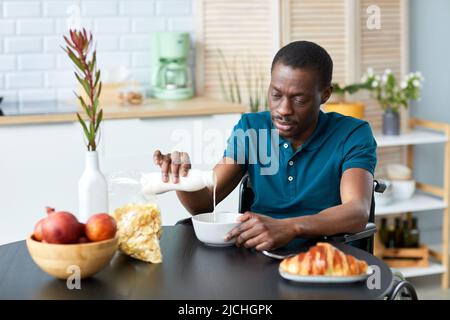 Portrait of black adult man with disability enjoying light breakfast in elegant home kitchen, copy space Stock Photo