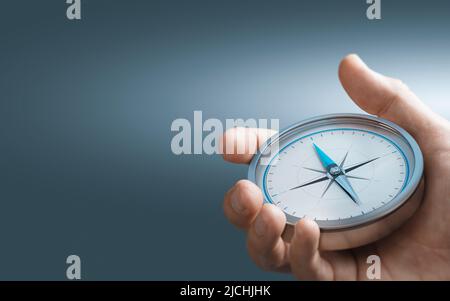 Hand holding a compass over blue background with copy space. Concept of Strategic orientation in business or marketing. Composite image between a 3d i Stock Photo
