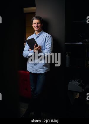 Portrait of successful confident prosperous mature businessman, interior designer, entrepreneur with a digital tablet in his hands posing for camera l Stock Photo