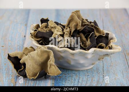 dried mushrooms known as jew's ear or ear fungus, in ceramic dish, on old wood plank table, popular in Asian cuisine Stock Photo