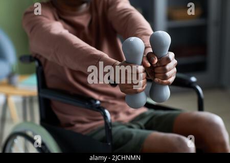 Closeup of African American man with disability exercising at home using dumbbell, copy space Stock Photo