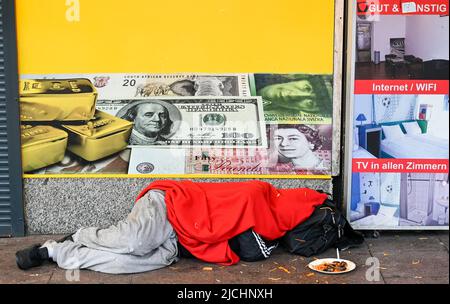 GERMANY, Hamburg, Reeperbahn, St. Pauli red light district, sleeping homeless person infront of closed money exchange shop, increasing poverty due to Corona pandemic and inflation crisis Stock Photo