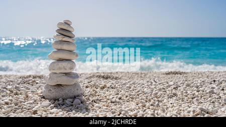Stacked stones on a beautiful white pebble beach in the Mediterranean Stock Photo