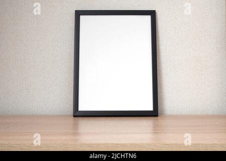 Black photo frame with blank white space on wooden shelf, desk. Mockup, template space for text Stock Photo