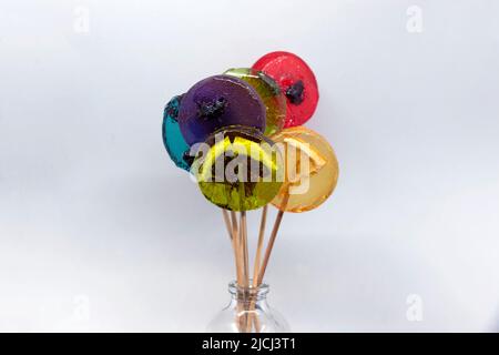 Colored lollipops with different berries and fruits inside in a bottle on a white background. Stock Photo