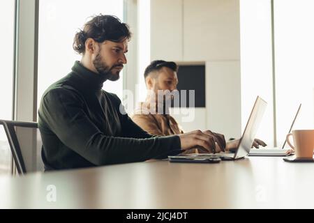 Focused company employees using laptops, working with pc devices at modern open space office Stock Photo