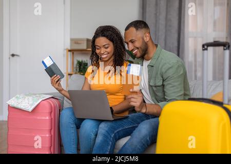 Family tours concept. Happy african american family with packed suitcases and passports with tickets, using laptop Stock Photo