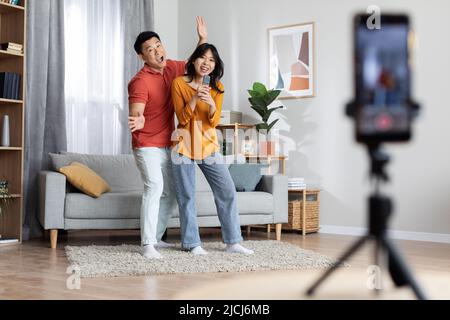 Cheerful japanese couple broadcasting while having fun at home Stock Photo