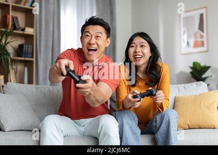 Excited funny korean couple playing video games at home Stock Photo