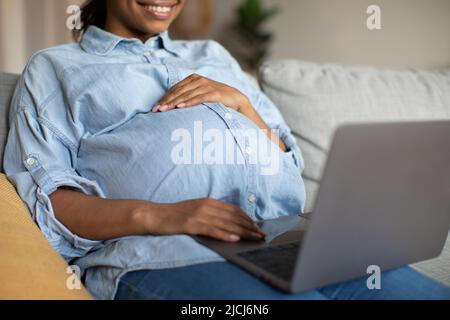 Unrecognizable Pregnant Black Female Using Laptop Computer Sitting At Home Stock Photo
