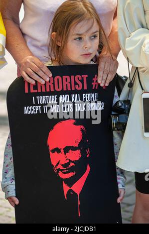 A young Ukrainian girl holds a placard denouncing Putin the terrorist during a demonstration outside the Russian embassy in The Hague. Ukrainians refugees and supporters celebrated ‘Russia Day' outside the Russian embassy in The Hague. A national holiday in the Russian Federation and celebrated annually on the 12 June. This day was officially known as the ‘Day of Adoption of the Declaration of State Sovereignty of the Russian Federation'; and has the unofficial title of “Independence Day”. Today's protesters mockingly referred to it as President Putin's last birthday! (Photo by Charles M. Vell Stock Photo