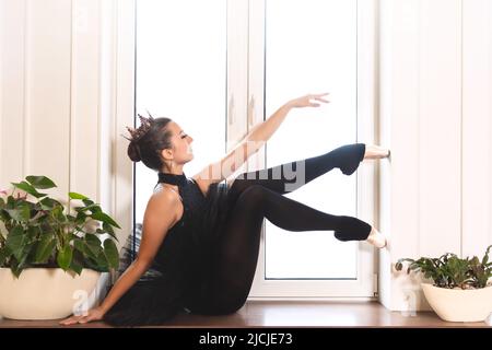 graceful ballerina in black swan dress against white background. Young ballet dancer practicing before performance in black tutu, classical dance stud Stock Photo