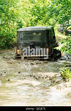 Back view of green russian off-road utility vehicle UAZ Hunter broke down, jammed on dirty road in forest among trees. Stock Photo