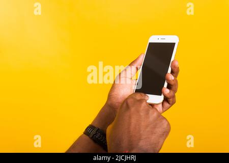 Closeup Asian happy portrait young black man holding digital mobile smartphone blank screen space on hands, studio isolated on yellow background Stock Photo