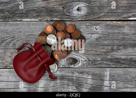 Small red leather bag of United States vintage coins on rustic wood background Stock Photo