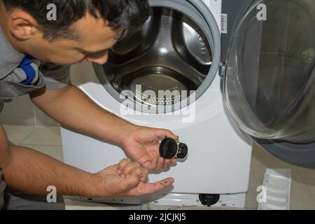 Picture of a plumber repairing a washing machine showing his dirty finger and the effectiveness of cleaning the filter and limescale Stock Photo