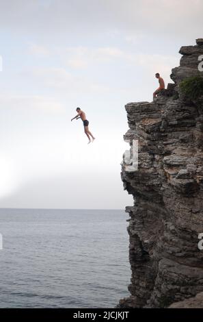 A man is jumping from a high cliff into the sea Stock Photo