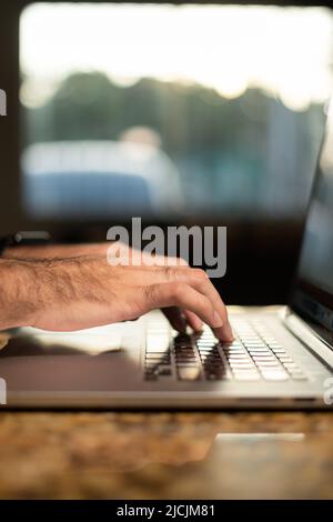Hands of a business man professional user professional worker using typing on laptop keyboard sit at home office desk working online. Stock Photo