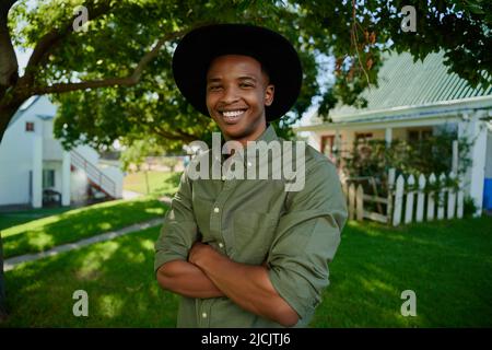 Mixed race male farmer standing by traditional farm house  Stock Photo