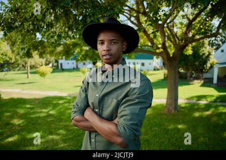 Mixed race farmer looking serious while standing outdoors with arms crossed Stock Photo