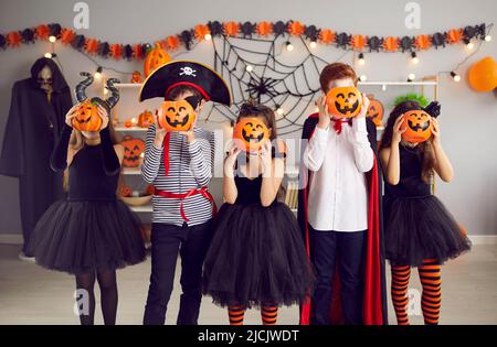 Children group in masquerade costumes pose with pumpkins Stock Photo