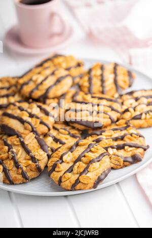 Chip cookies with peanuts and chocolate strips on a white table. Stock Photo