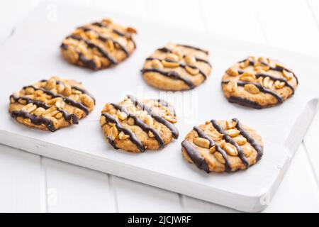 Chip cookies with peanuts and chocolate strips on a white table. Stock Photo